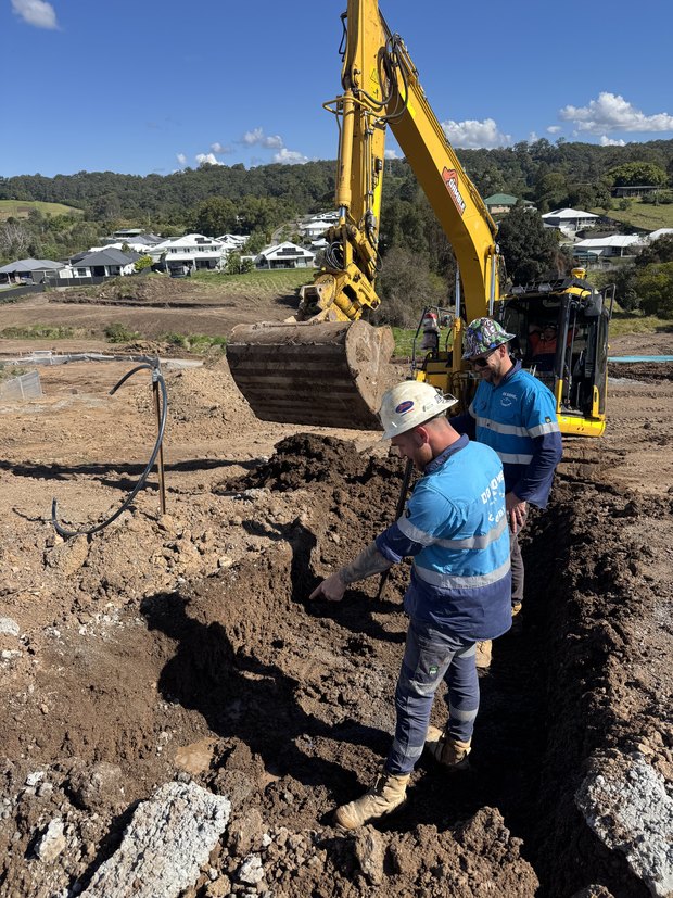 Excavator and crew working a trench on a new estate civil site