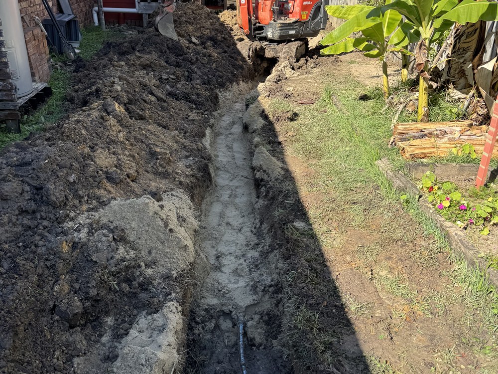 Trench excavated alongside a house to reach an underground pipe leak